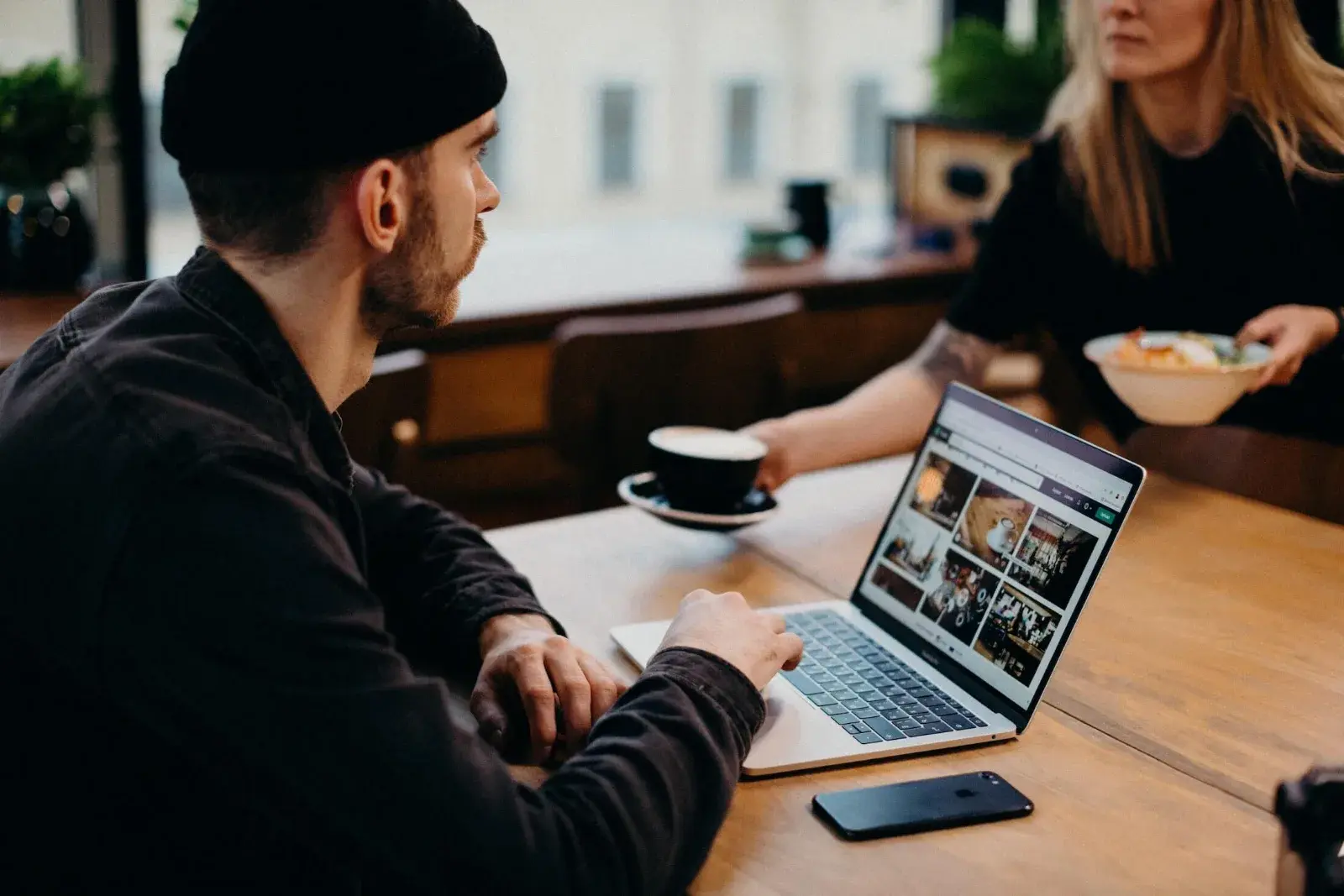 Two colleagues working with a laptop at a café table