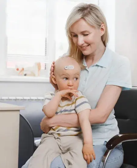 Mother holding her baby, who wears a health monitoring sensor